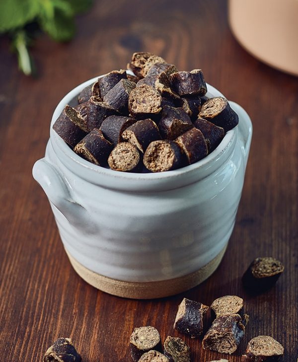 A small ceramic pot on wooden surface filled with James & Ella's air-dried training treats