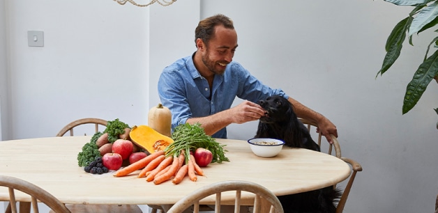 James middleton sat at table feeding treat to black cocker spaniel