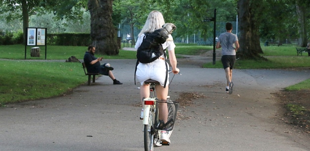 Girl riding on bike with small dog in backpack