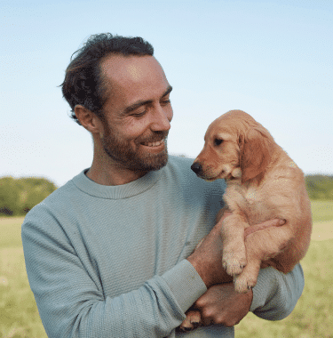 James Middleton holding a golden retriever puppy