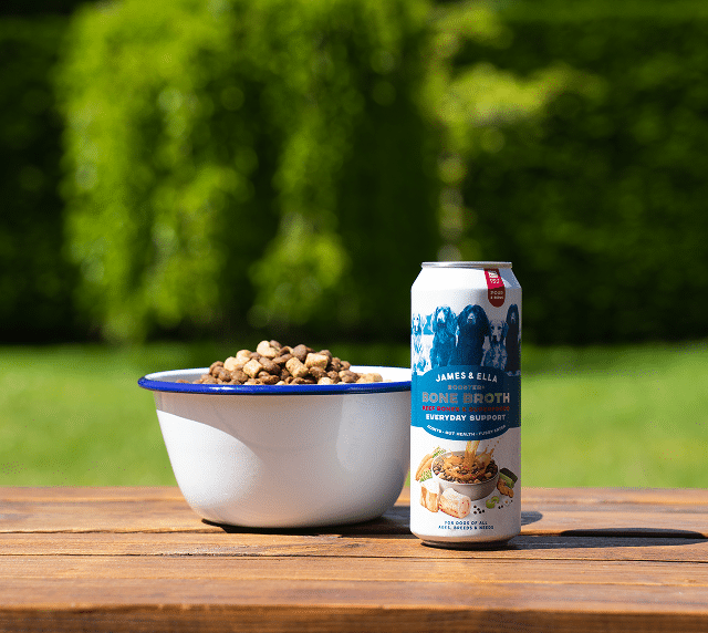 a dog bowl filled with kibble with a can of bone broth
